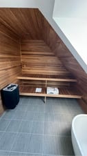 Specialbygget sauna med træpaneler, bænke og skrå loftslinje Specialbygget sauna med træpaneler, bænke og skrå loftslinje